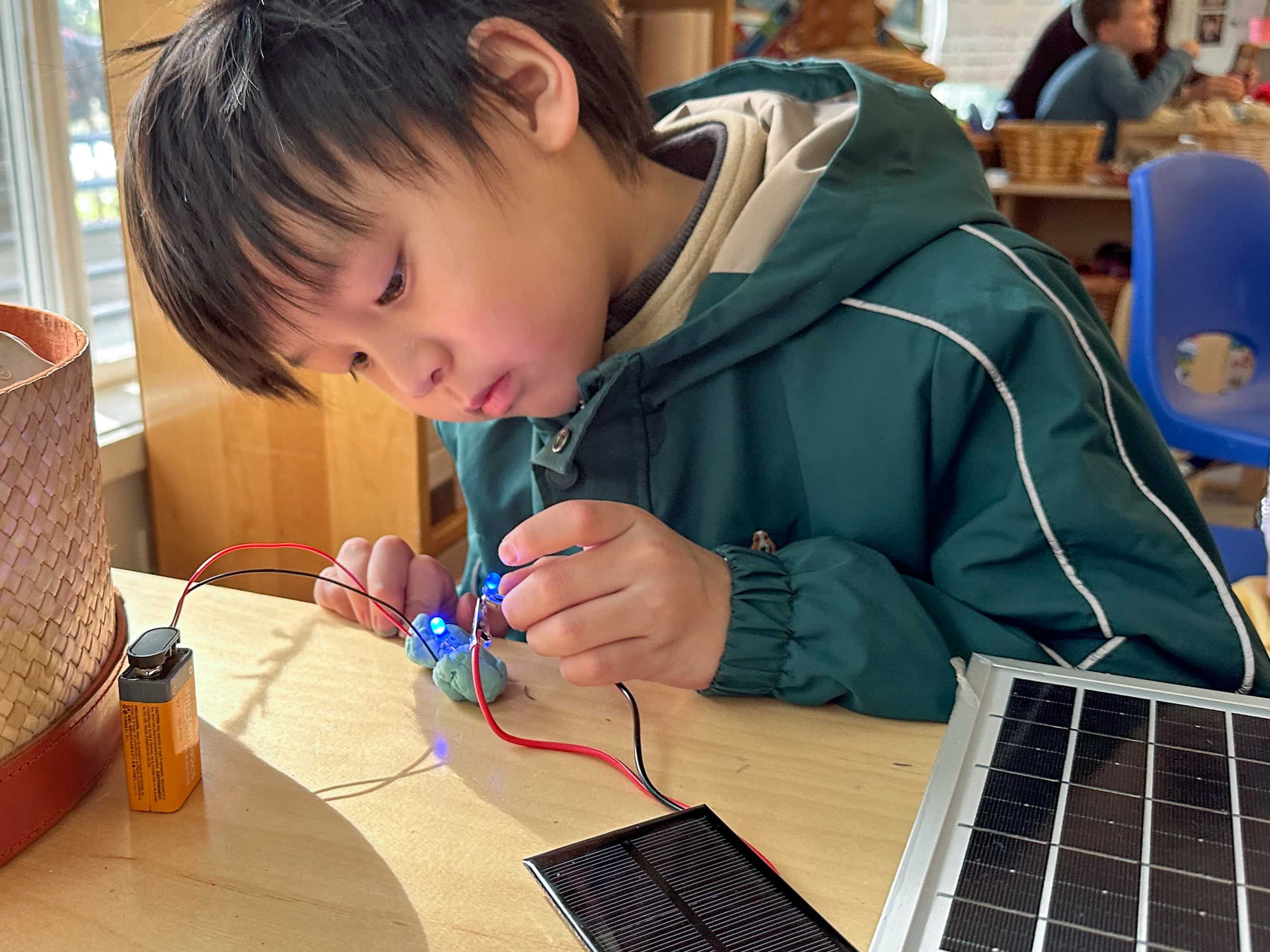 A child wiring a circuit to a battery