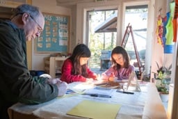 Two students and a grandparent working together at a classroom table
